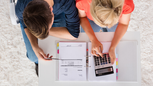 Aerial view of male/female couple reviewing documents with a calculator in front of them
