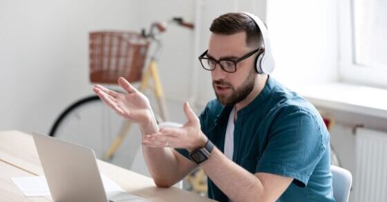 Remote sale by a white male wearing a headset and talking with hand gestures n front of a laptop with a city bike in the background